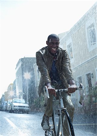 Happy businessman riding bicycle in rain Foto de stock - Sin royalties Premium, Código: 6113-06899576