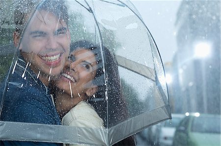 sharing - Happy couple hugging under umbrella in rain Stock Photo - Premium Royalty-Free, Code: 6113-06899582