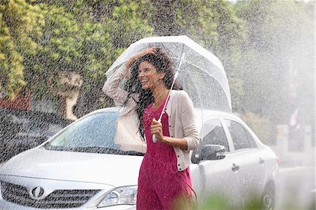 Happy woman with umbrella in rain Stock Photo - Premium Royalty-Free, Code: 6113-06899597