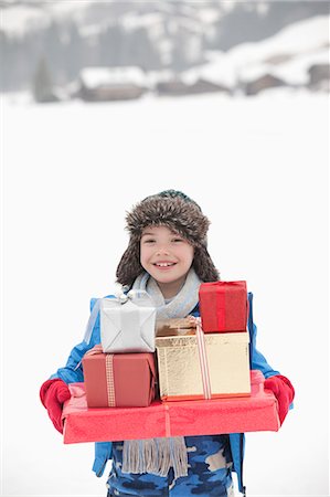 fur (animal hair) - Portrait of smiling boy carrying stack of Christmas gifts in snow Stock Photo - Premium Royalty-Free, Code: 6113-06899507