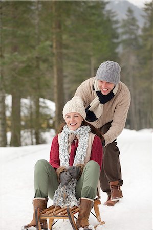 Happy couple sledding in snowy woods Stock Photo - Premium Royalty-Free, Code: 6113-06899513