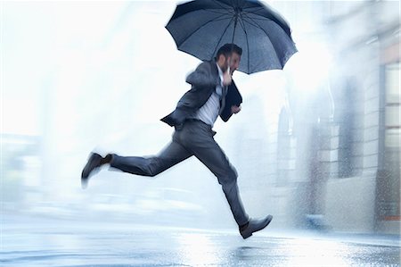 Businessman running with umbrella in rainy street Foto de stock - Sin royalties Premium, Código: 6113-06899524