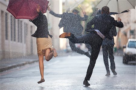 Business people with umbrellas dancing in rain Photographie de stock - Premium Libres de Droits, Code: 6113-06899533
