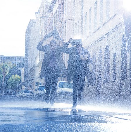 Businessmen covering heads with newspaper in rain Stock Photo - Premium Royalty-Free, Code: 6113-06899530