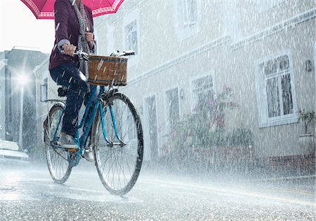 rainy day - Woman riding bicycle with umbrella in rainy street Foto de stock - Sin royalties Premium, Código: 6113-06899535