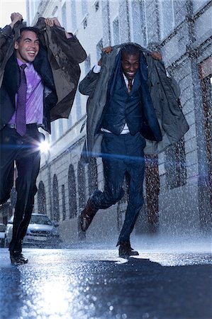 enthusiastic business man - Happy businessmen covering heads with coats in rainy street Stock Photo - Premium Royalty-Free, Code: 6113-06899603