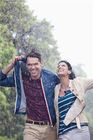 Happy couple walking in rain Stock Photo - Premium Royalty-Free, Code: 6113-06899620