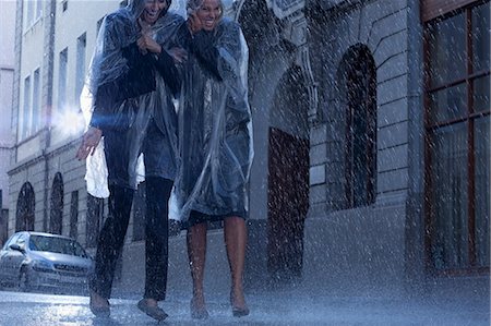 Businesswomen in ponchos walking in rainy street Stock Photo - Premium Royalty-Free, Code: 6113-06899624
