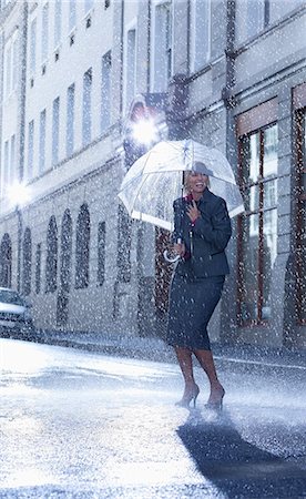 rushing - Businesswoman under umbrella in rainy street Foto de stock - Sin royalties Premium, Código: 6113-06899634