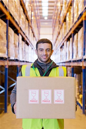 Worker carrying "fragile" box in warehouse Stock Photo - Premium Royalty-Free, Code: 6113-06908452