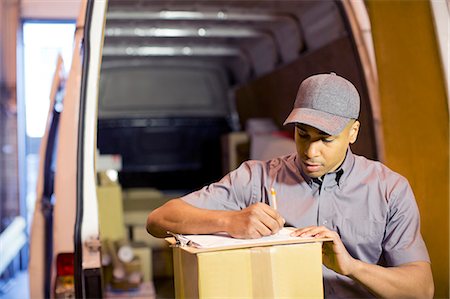 Delivery boy writing on clipboard in van Photographie de stock - Premium Libres de Droits, Code: 6113-06908455