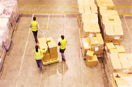 Workers carting boxes in warehouse Stock Photo - Premium Royalty-Free, Code: 6113-06908407