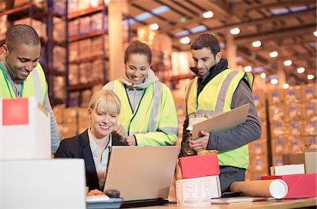 Businesswoman and workers using laptop in warehouse Stock Photo - Premium Royalty-Free, Code: 6113-06908436