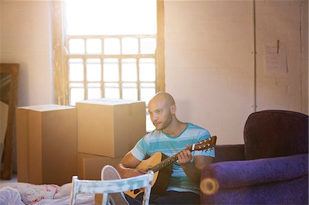 Man playing guitar in new home Foto de stock - Royalty Free Premium, Número: 6113-06908571