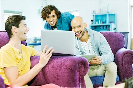 Men using laptop together in living room Stock Photo - Premium Royalty-Free, Code: 6113-06908582