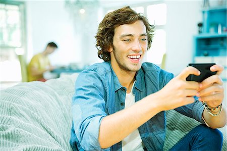 Man using cell phone in beanbag chair Stock Photo - Premium Royalty-Free, Code: 6113-06908654