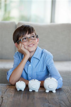 simsearch:6113-07242219,k - Boy sitting with piggy banks at coffee table Foto de stock - Sin royalties Premium, Código: 6113-06908676