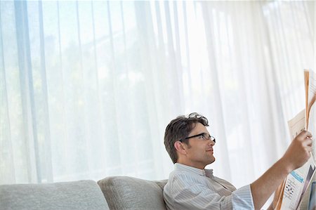 eyeglasses and newspaper - Man reading newspaper on sofa Stock Photo - Premium Royalty-Free, Code: 6113-06908699
