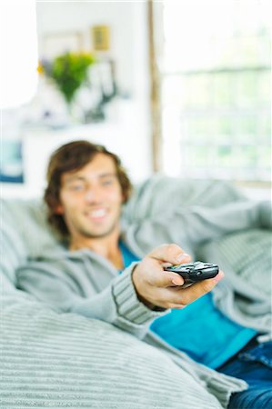 Man watching television in beanbag chair Stock Photo - Premium Royalty-Free, Code: 6113-06908628