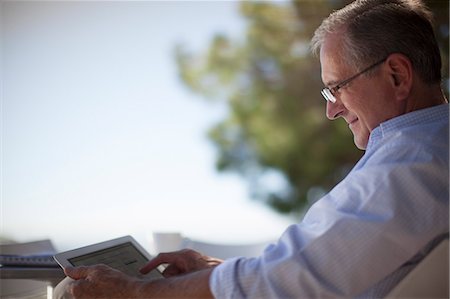 Older man using tablet computer outdoors Stock Photo - Premium Royalty-Free, Code: 6113-06908777