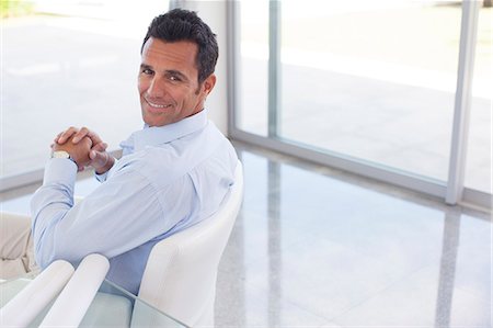 Businessman smiling in office chair Stock Photo - Premium Royalty-Free, Code: 6113-06908853