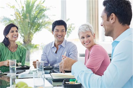 people eating at work - Business people smiling in lunch meeting Stock Photo - Premium Royalty-Free, Code: 6113-06908858