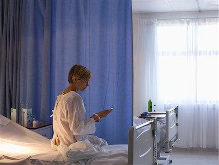 Patient using cell phone in hospital bed Stock Photo - Premium Royalty-Free, Code: 6113-06909069