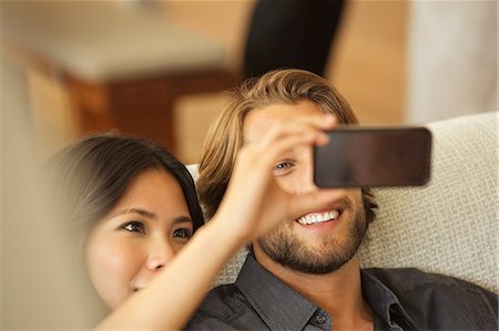 showing - Couple using cell phone as camera together on sofa Photographie de stock - Premium Libres de Droits, Code: 6113-06909086