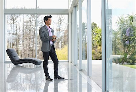 Businessman standing at office window Stock Photo - Premium Royalty-Free, Code: 6113-06909037