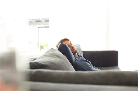 Smiling man relaxing on sofa Photographie de stock - Premium Libres de Droits, Code: 6113-06909261