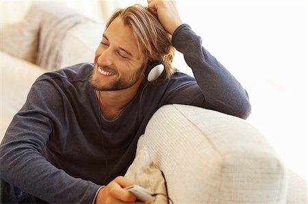 Man listening to headphones on sofa Photographie de stock - Premium Libres de Droits, Code: 6113-06909207