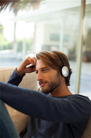 simsearch:6113-06909277,k - Man listening to headphones on sofa Foto de stock - Sin royalties Premium, Código: 6113-06909229