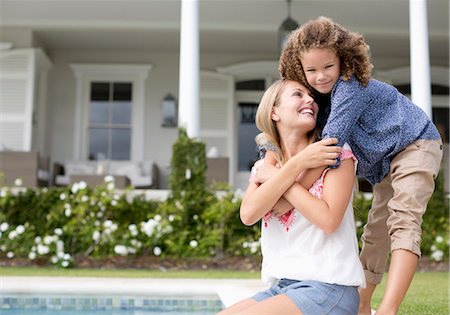 Mother and daughter hugging by swimming pool Photographie de stock - Premium Libres de Droits, Code: 6113-06909308