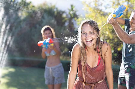 squirting - Friends playing with water guns in backyard Stock Photo - Premium Royalty-Free, Code: 6113-06909319