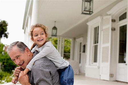 retirement outdoors - Older man carrying granddaughter piggy back on porch Stock Photo - Premium Royalty-Free, Code: 6113-06909423