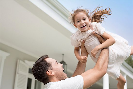 Father and daughter playing outside house Stock Photo - Premium Royalty-Free, Image code: 6113-06909427