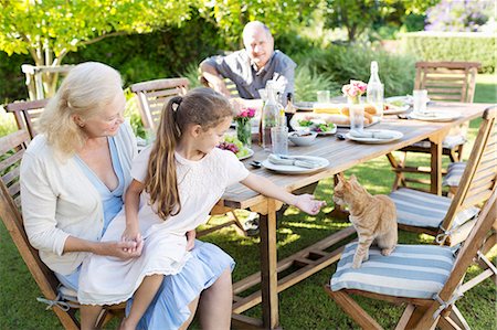 family with one child - Girl asking to pet cat at table outdoors Stock Photo - Premium Royalty-Free, Code: 6113-06909428