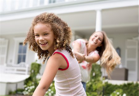 Mother and daughter playing outside house Photographie de stock - Premium Libres de Droits, Code: 6113-06909436