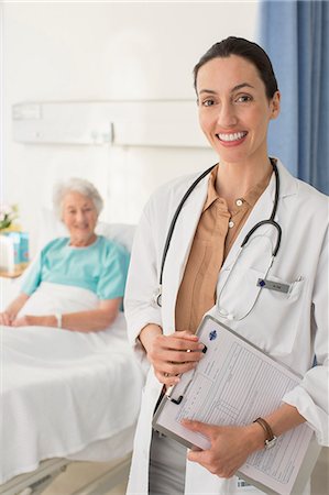 sick senior - Portrait of smiling doctor with senior patient in background Stock Photo - Premium Royalty-Free, Code: 6113-07146760