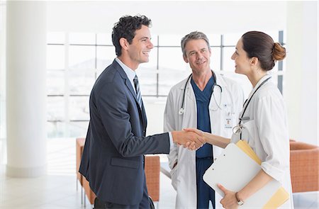 Doctor and businessman handshaking in hospital lobby Foto de stock - Sin royalties Premium, Código: 6113-07146784