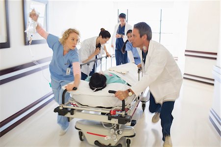 Doctors rushing patient on gurney in hospital corridor Photographie de stock - Premium Libres de Droits, Code: 6113-07146701