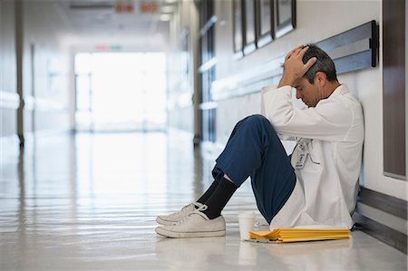 stress coffee - Doctor sitting on floor in hospital corridor with head in hands Stock Photo - Premium Royalty-Free, Code: 6113-07146738