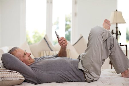 Senior man using cell phone on bed Foto de stock - Sin royalties Premium, Código: 6113-07146874