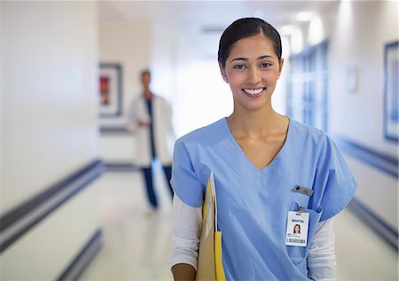 portrait of a woman and healthcare - Portrait of smiling nurse in hospital corridor Stock Photo - Premium Royalty-Free, Code: 6113-07146801