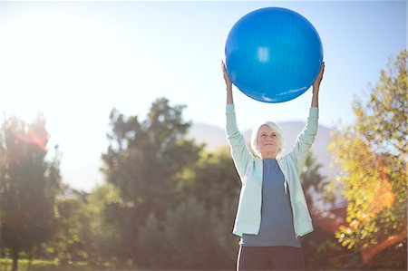 sun flare energy - Senior woman holding fitness ball in park Stock Photo - Premium Royalty-Free, Code: 6113-07146837