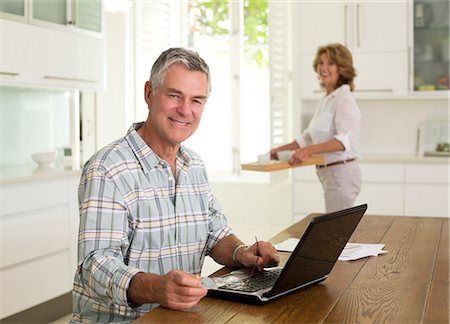 e-mail - Portrait of smiling senior man using laptop in kitchen Photographie de stock - Premium Libres de Droits, Code: 6113-07146939