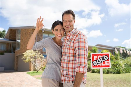for sale - Portrait of smiling couple holding keys in front of new house Stock Photo - Premium Royalty-Free, Code: 6113-07147156