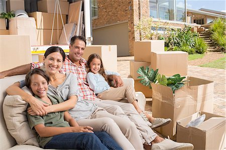 Portrait of smiling family sitting on sofa near moving van in driveway Stock Photo - Premium Royalty-Free, Code: 6113-07147177