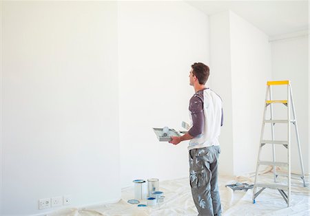 Man with paint tray looking up at white wall Photographie de stock - Premium Libres de Droits, Code: 6113-07147199