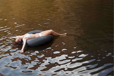 float - Woman floating in inner tube in river Stock Photo - Premium Royalty-Free, Code: 6113-07147107